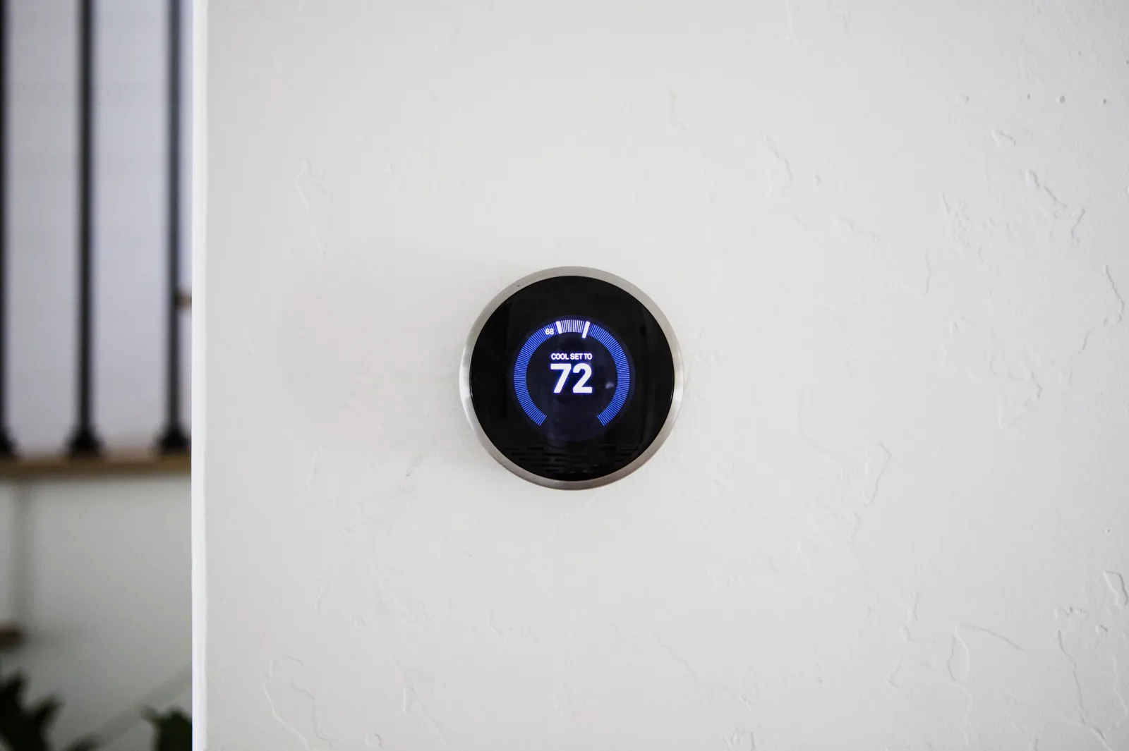 Round smart thermostat on a white wall showing cool set to 72