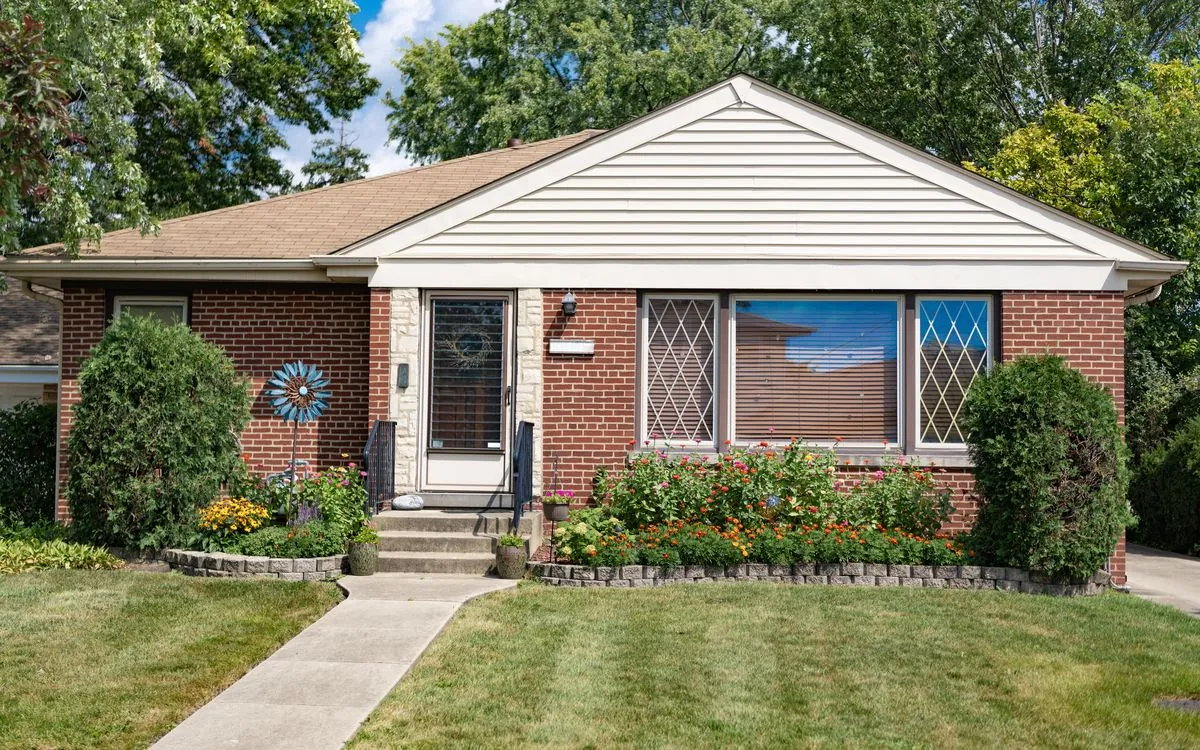 Single-storey red-brick house with a tan shingle roof, front garden and lawn