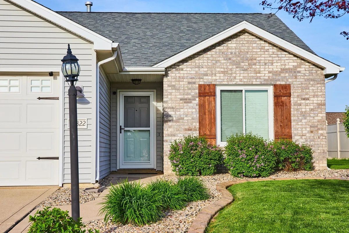 Single-storey brick home with a dark shingle roof, a front garden and lawn